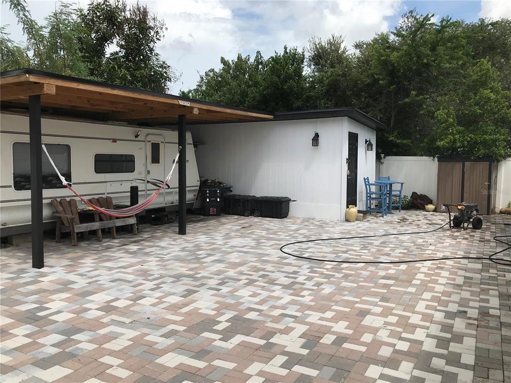 A paved patio area features a covered camper, a white shed, and outdoor furniture — 6908 N 21ST STREET, TAMPA, FL