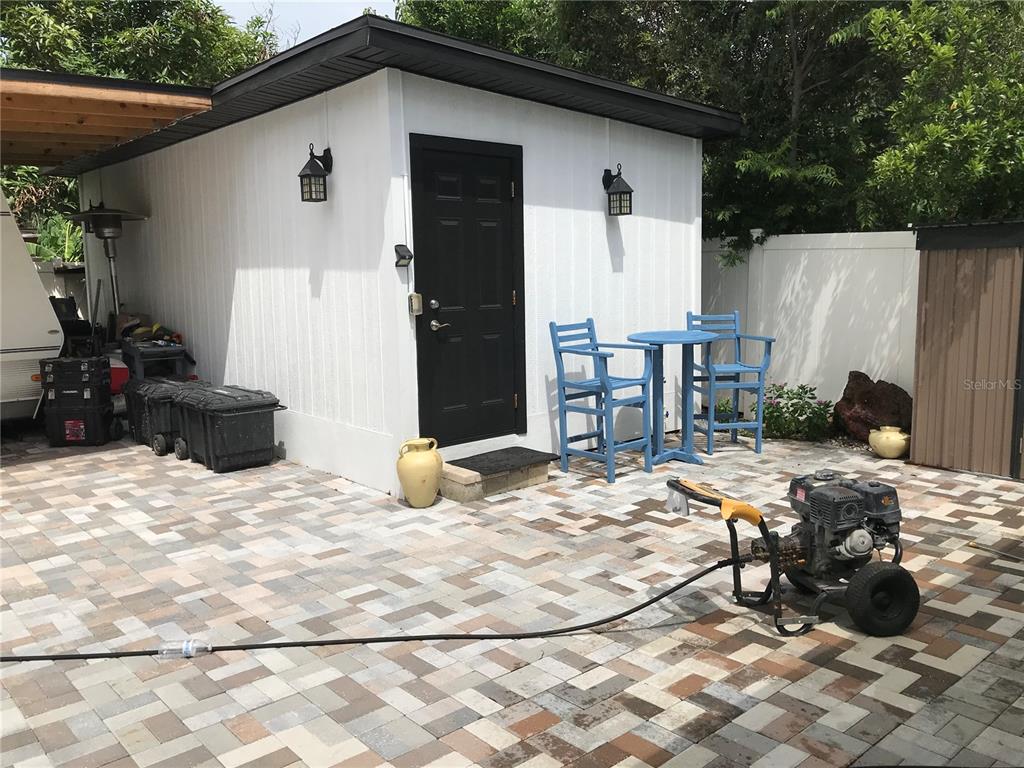 A white shed with a black door and a patio featuring a pressure washer — 6908 N 21ST STREET, TAMPA, FL