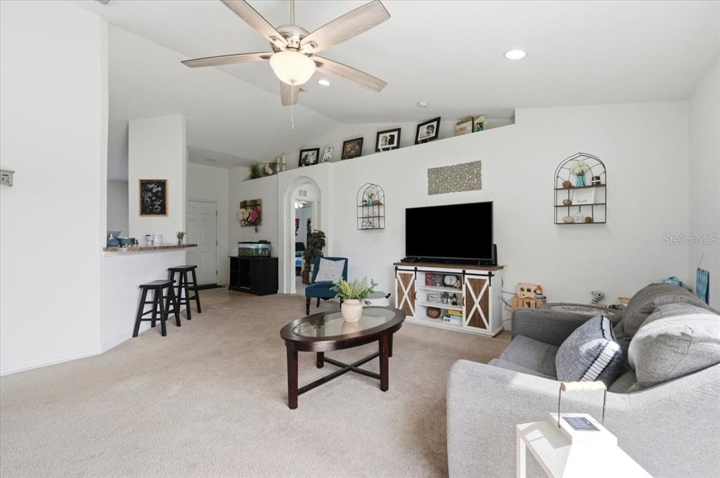 A tan single-story house features a dark front door, a concrete walkway, and landscaping — 180 SOLIS DRIVE, WINTER HAVEN, FL
