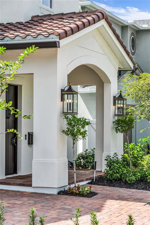 A white stucco home entrance features a tiled roof, arched porch, and two black lanterns — 1430 STETSON STREET, ORLANDO, FL