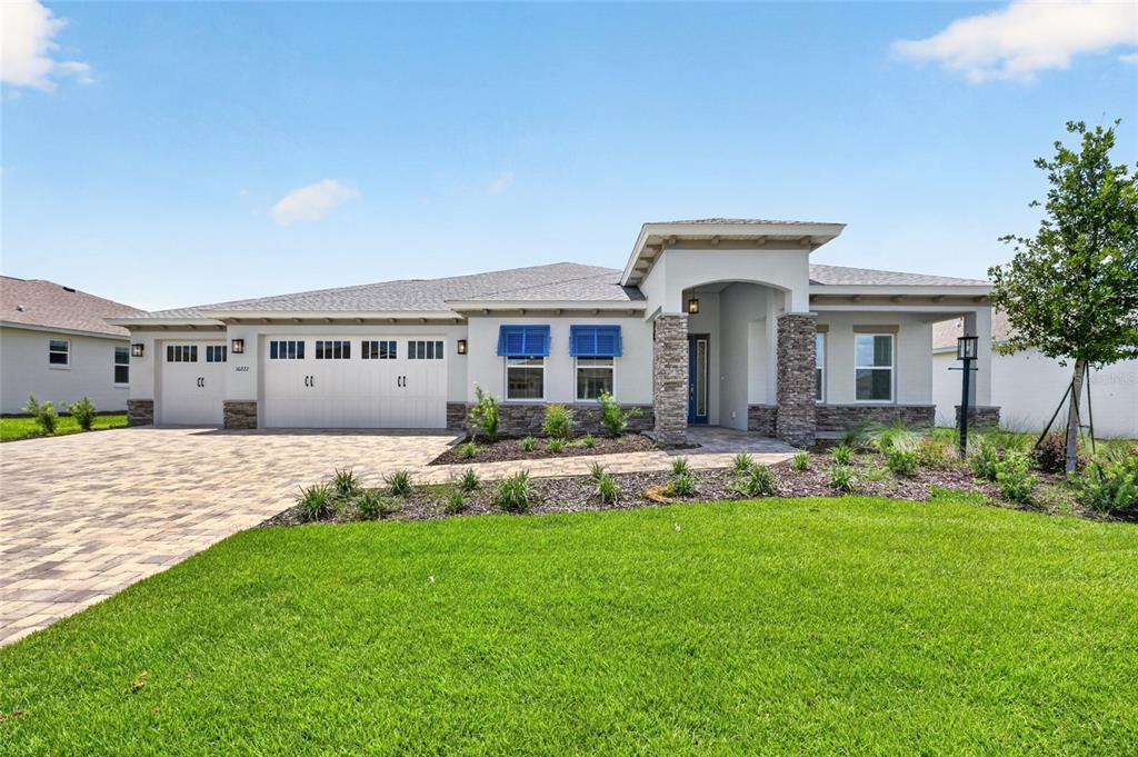 A single-story house with a stone-accented entryway, a three-car garage, and a paved driveway — 10222 SW 84TH STREET ROAD, OCALA, FL