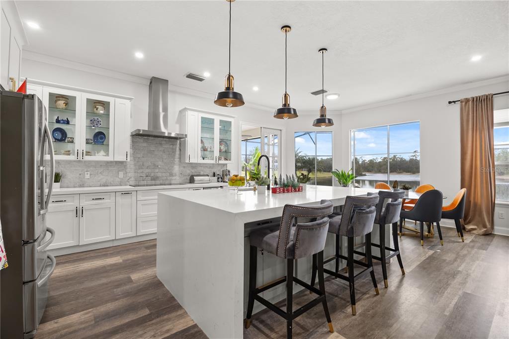 A modern kitchen features white cabinetry, a large quartz island, and views of a lake — 1746 CARILLON PARK DRIVE, OVIEDO, FL