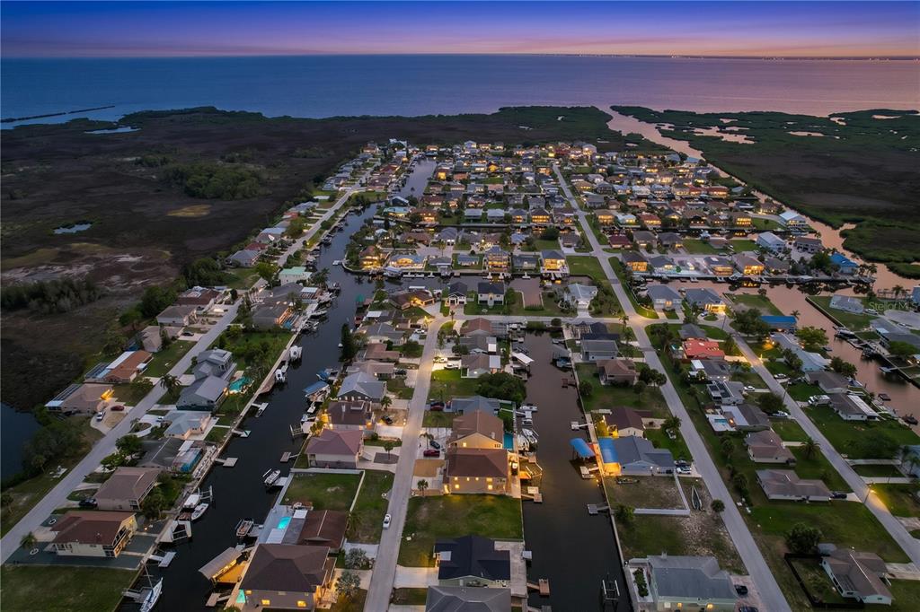 An aerial view of a waterfront residential neighborhood with canals and houses at dusk — 7401 ISLANDER LANE, HUDSON, FL