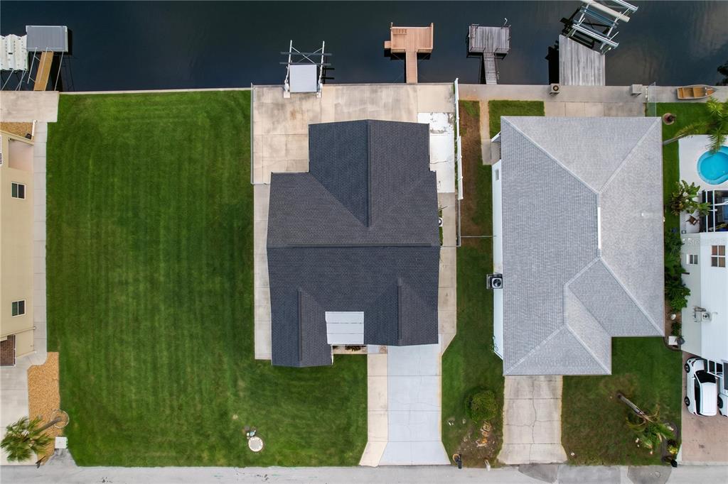 An aerial view shows two waterfront houses with driveways, lawns, and private boat docks — 7401 ISLANDER LANE, HUDSON, FL