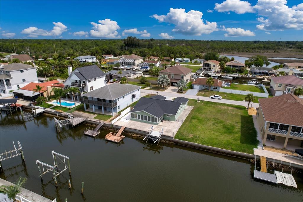 An aerial view shows waterfront houses with docks along a canal in a residential neighborhood — 7401 ISLANDER LANE, HUDSON, FL