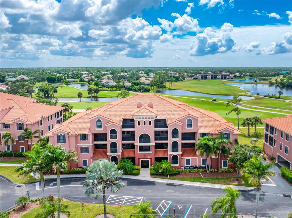 An aerial view shows a multi-story residential building with a red roof near a golf course — 24351 BALTIC AVE UNIT 203, PUNTA GORDA, FL