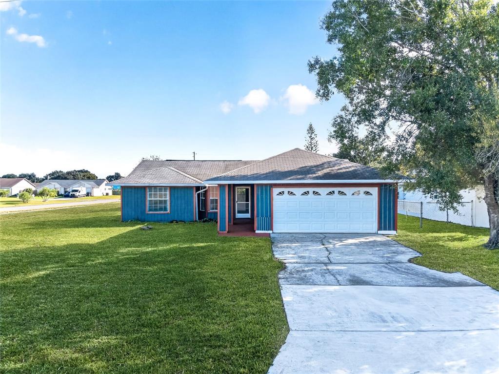 A blue single-story house with a white garage door and a concrete driveway — 602 CARIBOU COURT, POINCIANA, FL