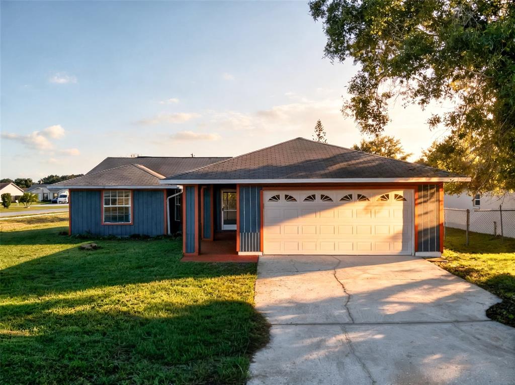 A single-story house with blue vertical siding, orange trim, and an attached two-car garage — 602 CARIBOU COURT, POINCIANA, FL