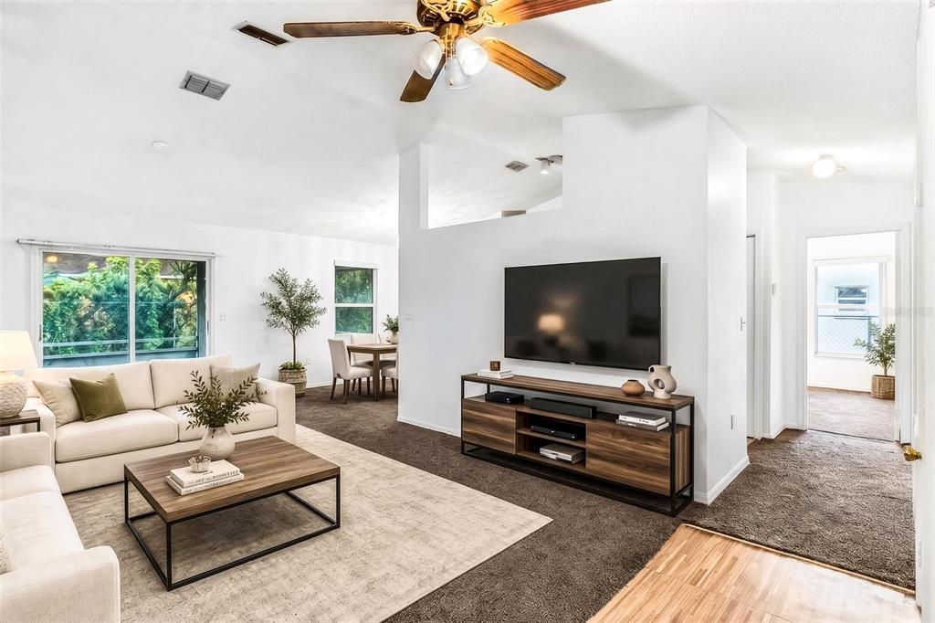 A living room features a white sofa, a wooden coffee table, and a wall-mounted television — 602 CARIBOU COURT, POINCIANA, FL