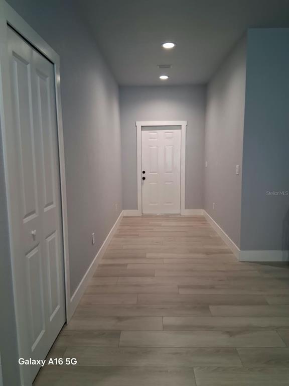 A kitchen island with bar stools faces a hallway leading to a white front door — 3219 E EMMA STREET, TAMPA, FL