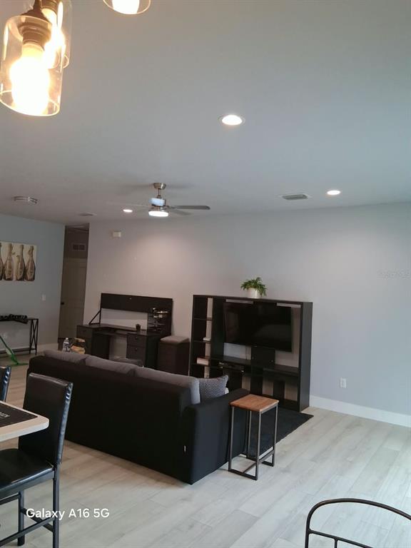 A living room features a black entertainment center, a desk, a sofa, and a ceiling fan — 3219 E EMMA STREET, TAMPA, FL