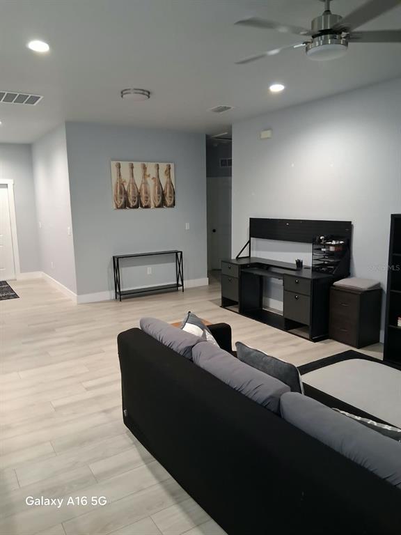 A living room features a dark sofa, a television console, a desk, and light flooring — 3219 E EMMA STREET, TAMPA, FL