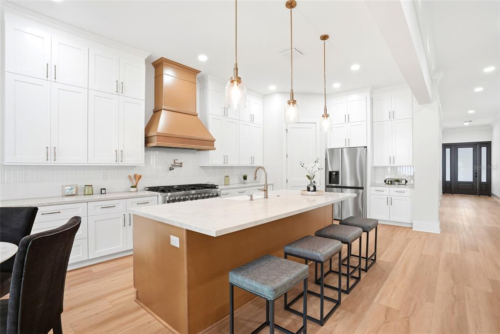 A modern kitchen features white cabinetry, a wood-toned island and range hood, and pendant lighting — 2376 RAJEL AVENUE, SAFETY HARBOR, FL