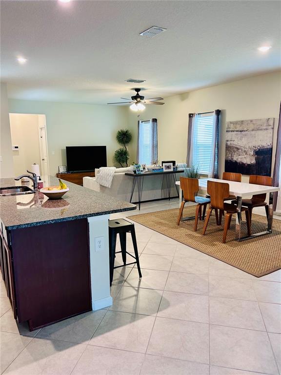 An open-concept kitchen with a granite island overlooks a living and dining area — 6168 GLORY BOWER DRIVE, WINTER GARDEN, FL