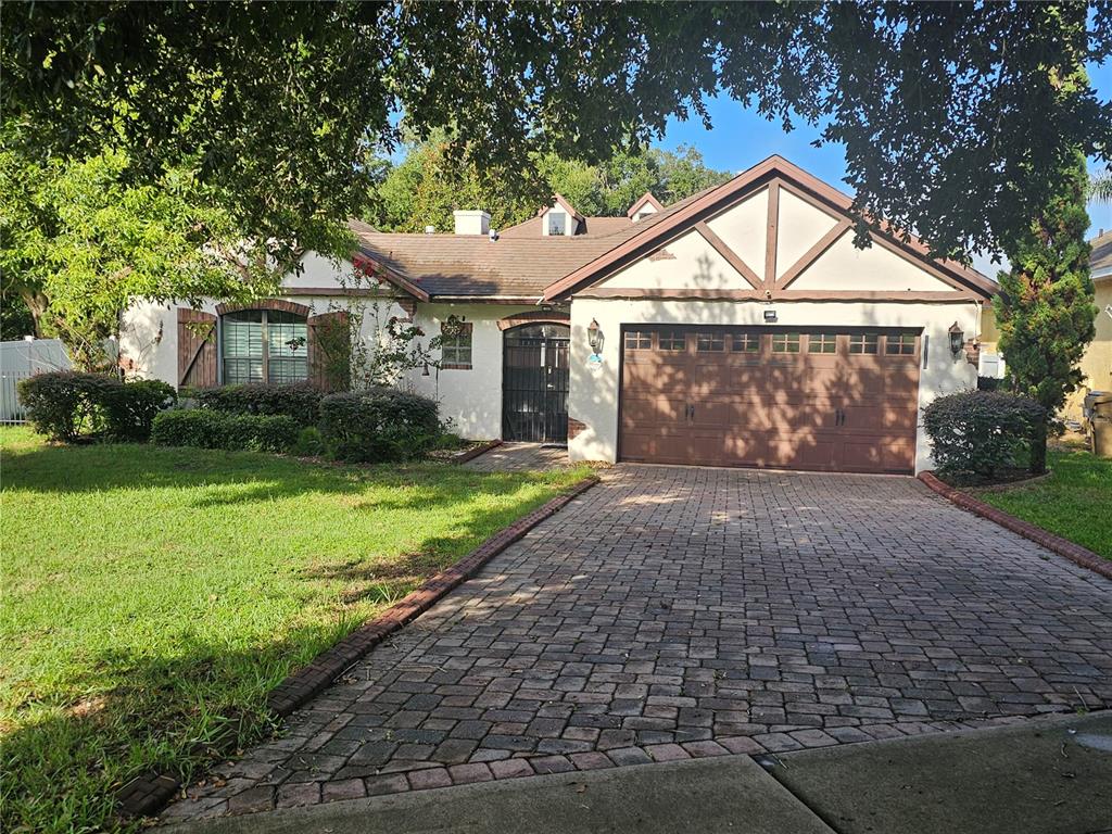A single-story house with a brick paver driveway, a two-car garage, and stucco siding — 33116 IRONGATE DRIVE, LEESBURG, FL