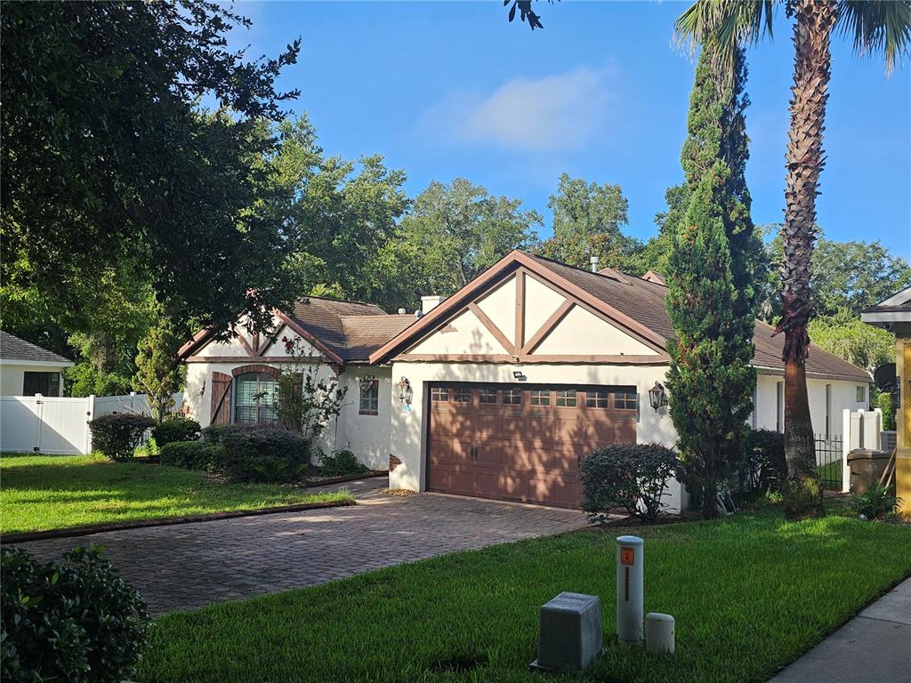 A single-story house with a brown garage door, stucco exterior, and a brick driveway — 33116 IRONGATE DRIVE, LEESBURG, FL