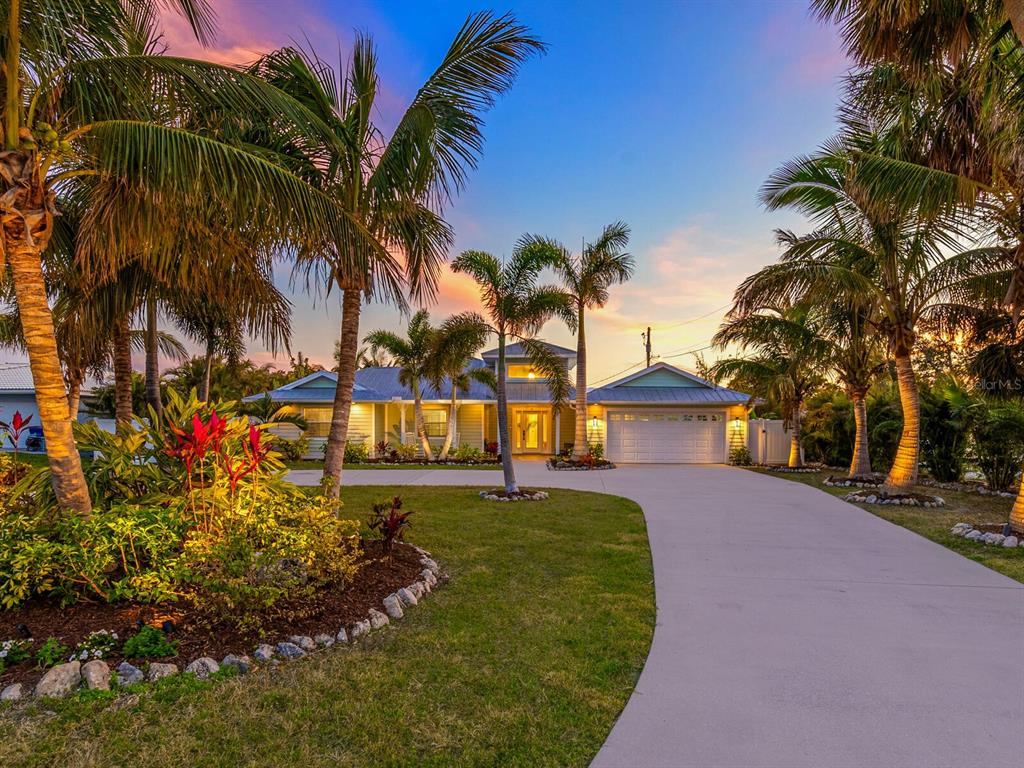A single-story house with a white garage and palm trees at sunset — 221 LYCHEE ROAD, NOKOMIS, FL
