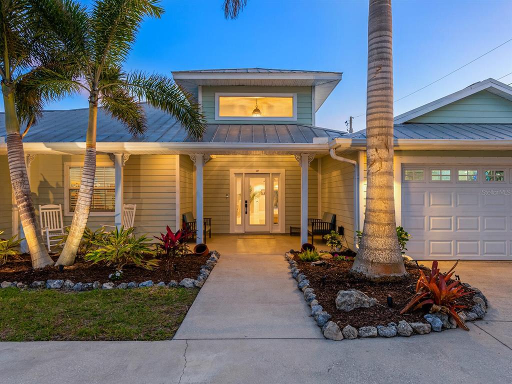 A single-story house with light green siding, a metal roof, and a palm-lined front walkway — 221 LYCHEE ROAD, NOKOMIS, FL