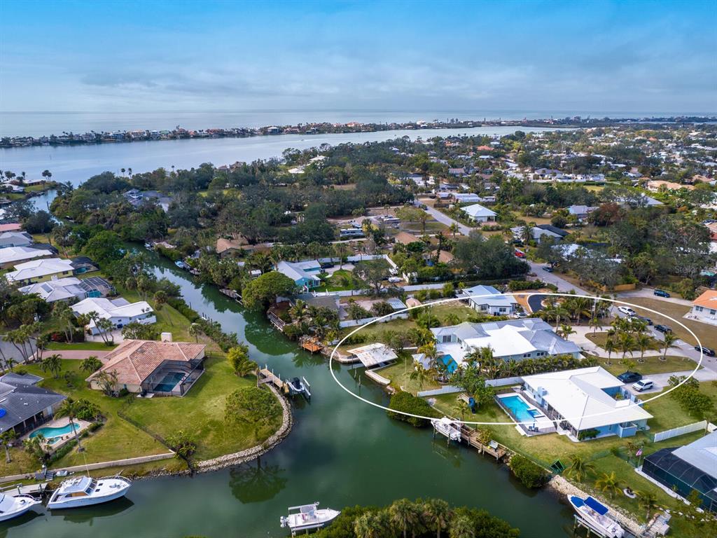 An aerial view shows a waterfront house with a pool and boat dock on a canal — 221 LYCHEE ROAD, NOKOMIS, FL
