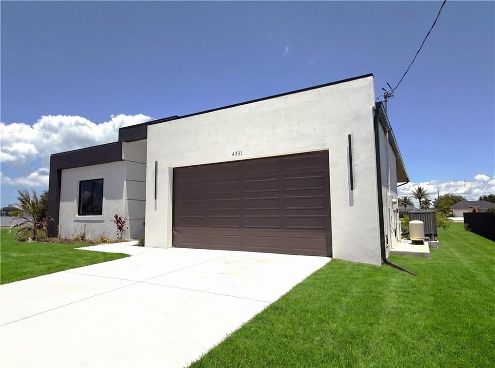 A modern, single-story house exterior with a white stucco facade and a brown garage door — 4331 NW 31ST TERRACE, CAPE CORAL, FL