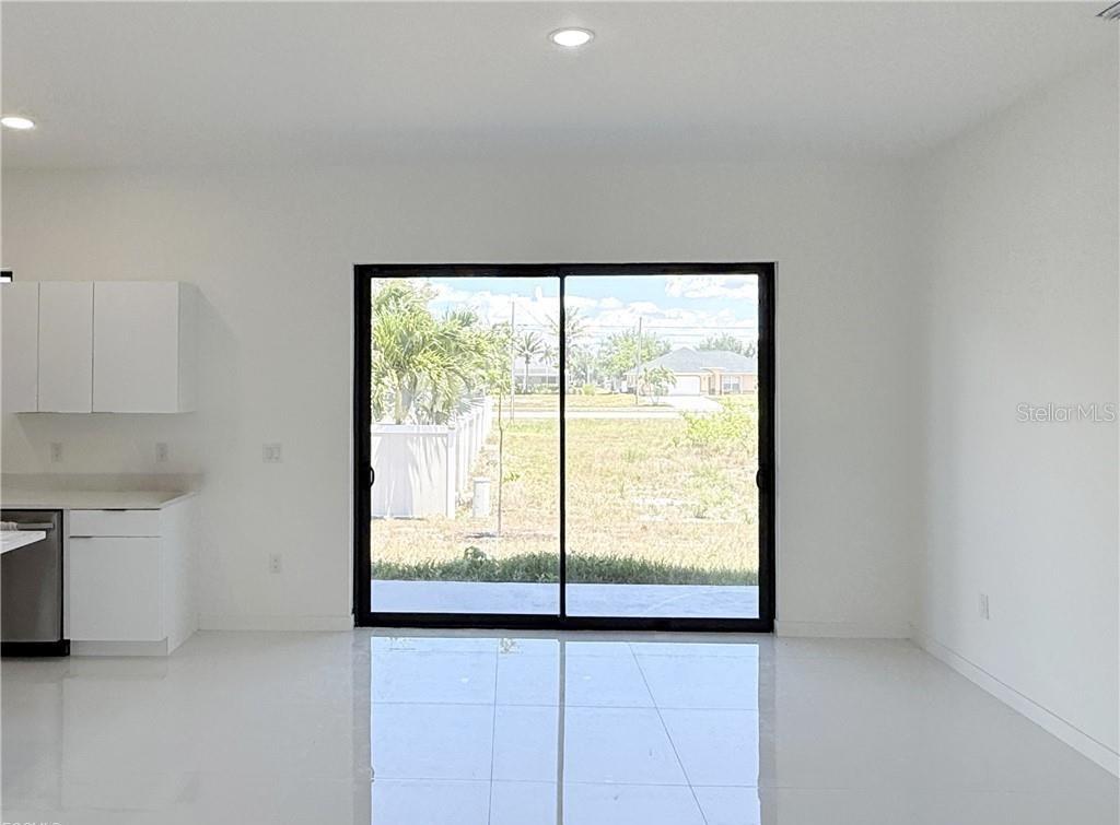 A bright, minimalist kitchen and living area features white tile floors and sliding glass doors — 4331 NW 31ST TERRACE, CAPE CORAL, FL