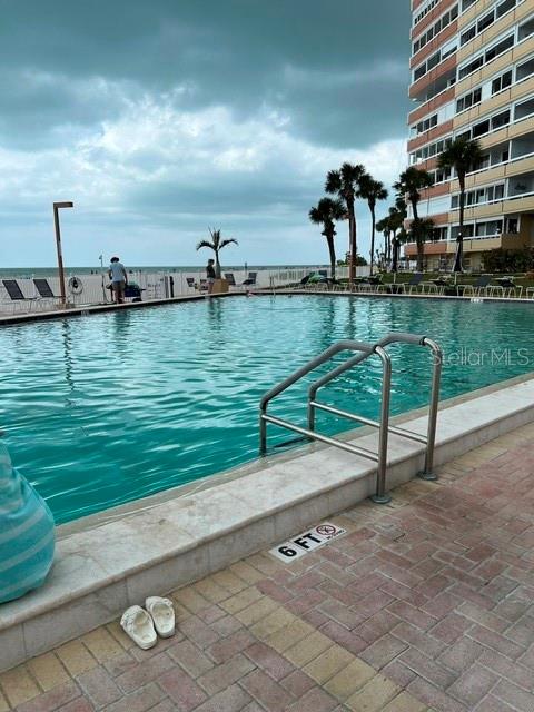 A swimming pool sits on a brick patio next to a tall beachfront residential building — 17920 GULF BOULEVARD UNIT 502, REDINGTON SHORES, FL