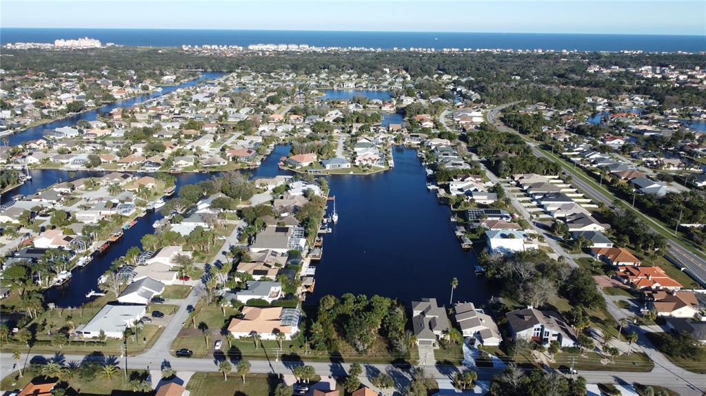 An aerial view shows a residential neighborhood with houses surrounding a large central canal — 10 CIMMARON DRIVE, PALM COAST, FL