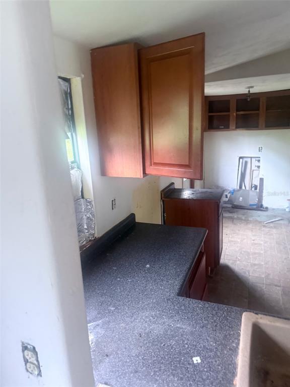 A kitchen features dark wood cabinets, a black countertop, and an unfinished floor — 13114 SE 32ND COURT, BELLEVIEW, FL