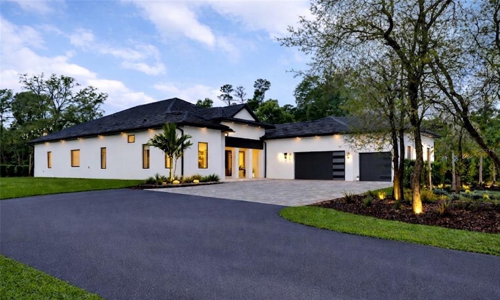 A modern white house with a dark roof, black garage doors, and a paved driveway — 8398 HAPPY TRAIL, KISSIMMEE, FL
