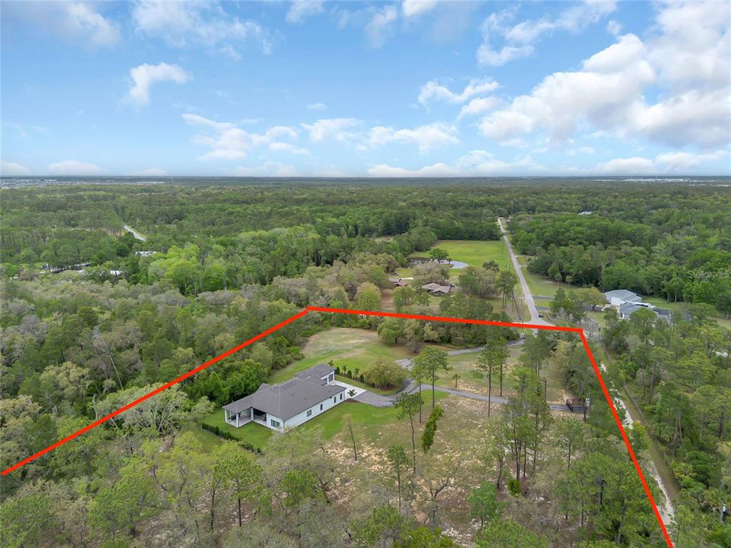 An aerial view shows a house on a large, wooded lot outlined in red — 8398 HAPPY TRAIL, KISSIMMEE, FL