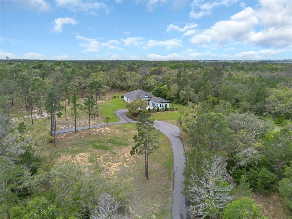 An aerial view shows a house with a long driveway surrounded by a wooded lot — 8398 HAPPY TRAIL, KISSIMMEE, FL