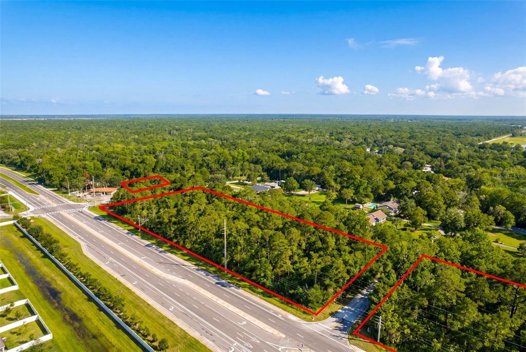 An aerial view shows several wooded lots outlined in red adjacent to a paved road — 2895 W INDIAN RIVER BLVD, EDGEWATER, FL