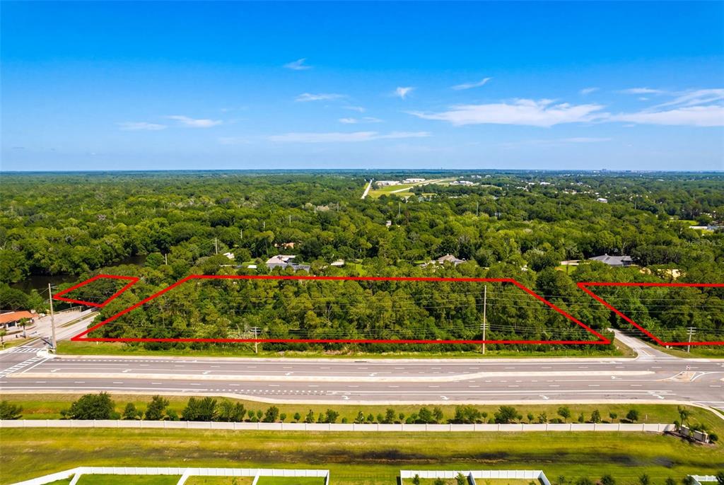 An aerial view shows a rectangular plot of wooded land outlined in red along a road — 2895 W INDIAN RIVER BLVD, EDGEWATER, FL