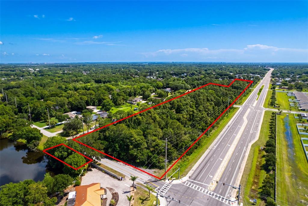 An aerial view shows a large, wooded plot of land outlined in red beside a highway — 2895 W INDIAN RIVER BLVD, EDGEWATER, FL