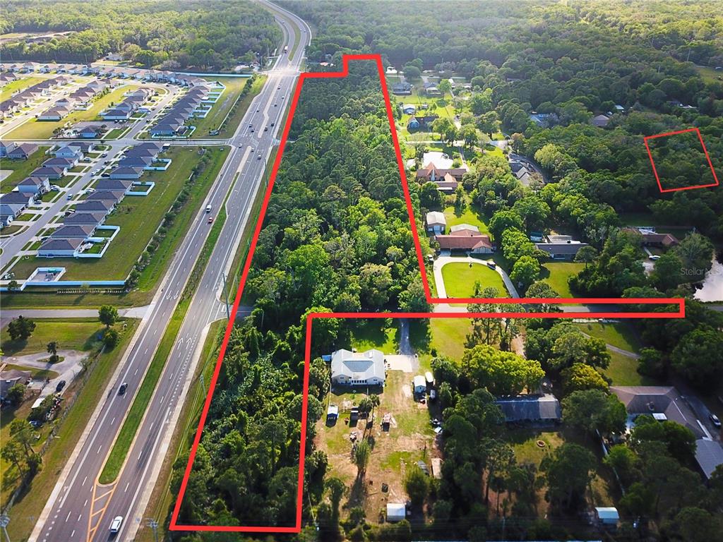 An aerial view shows a large, wooded plot of land outlined in red near a highway — 2895 W INDIAN RIVER BLVD, EDGEWATER, FL
