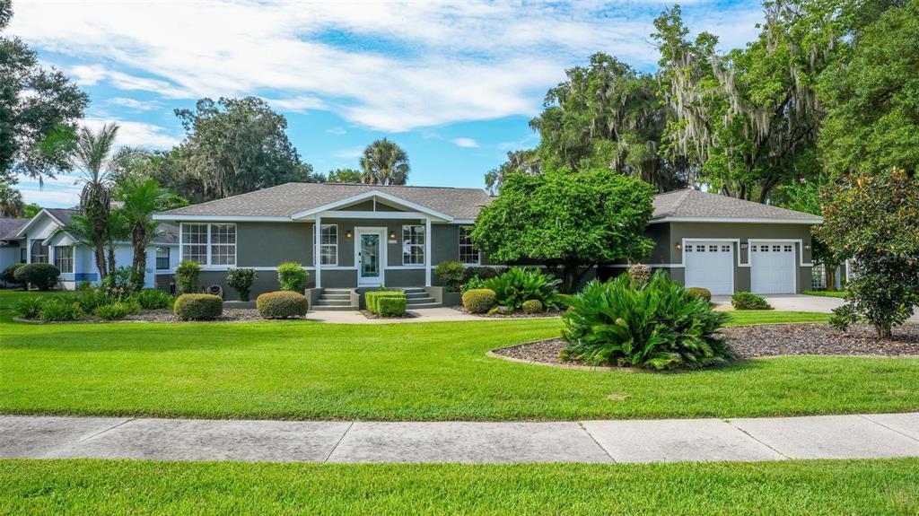 A single-story house with a green exterior, a two-car garage, and a large front lawn — 20368 THE GRANADA, DUNNELLON, FL