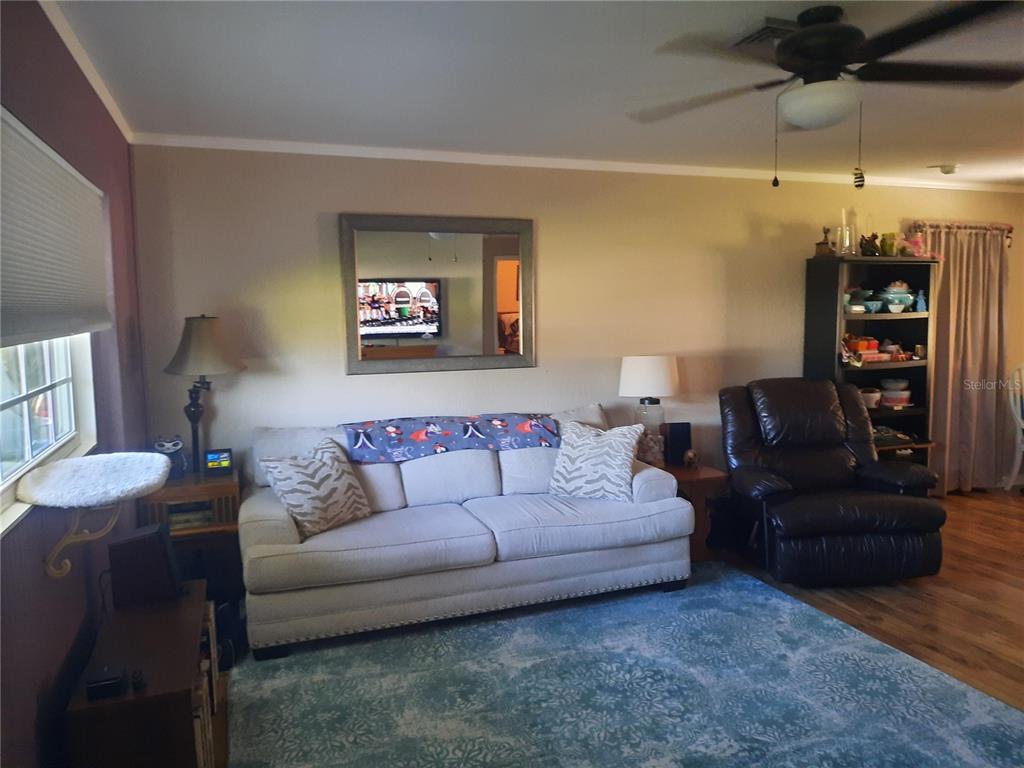 A living room features a light-colored sofa, a dark leather recliner, and a blue rug — 6554 MALALUKA ROAD, NORTH PORT, FL
