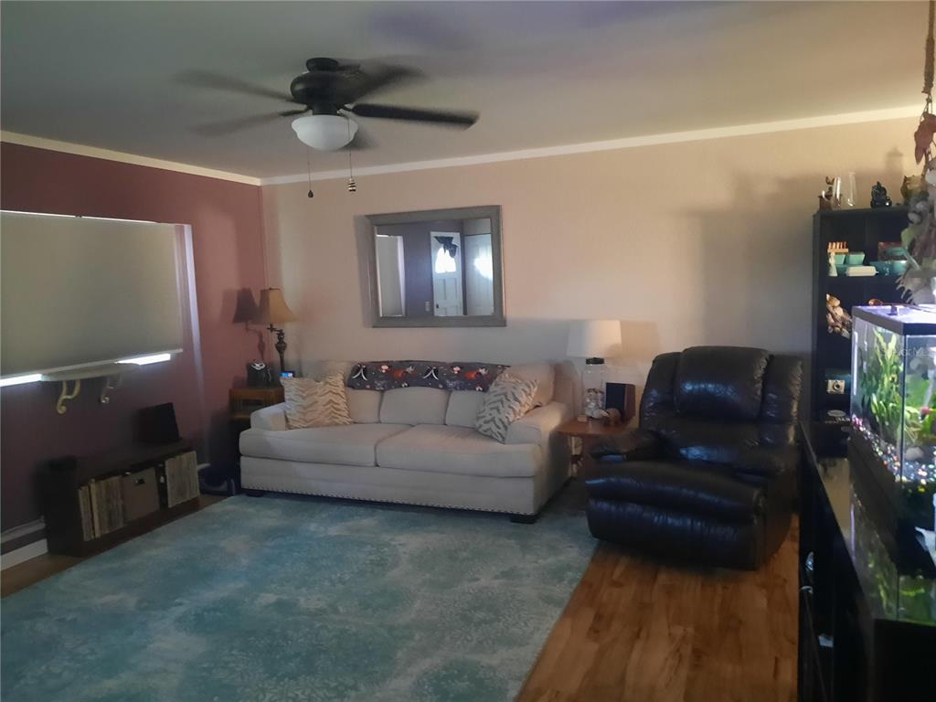 A living room features a beige sofa, a dark leather recliner, and a blue area rug — 6554 MALALUKA ROAD, NORTH PORT, FL