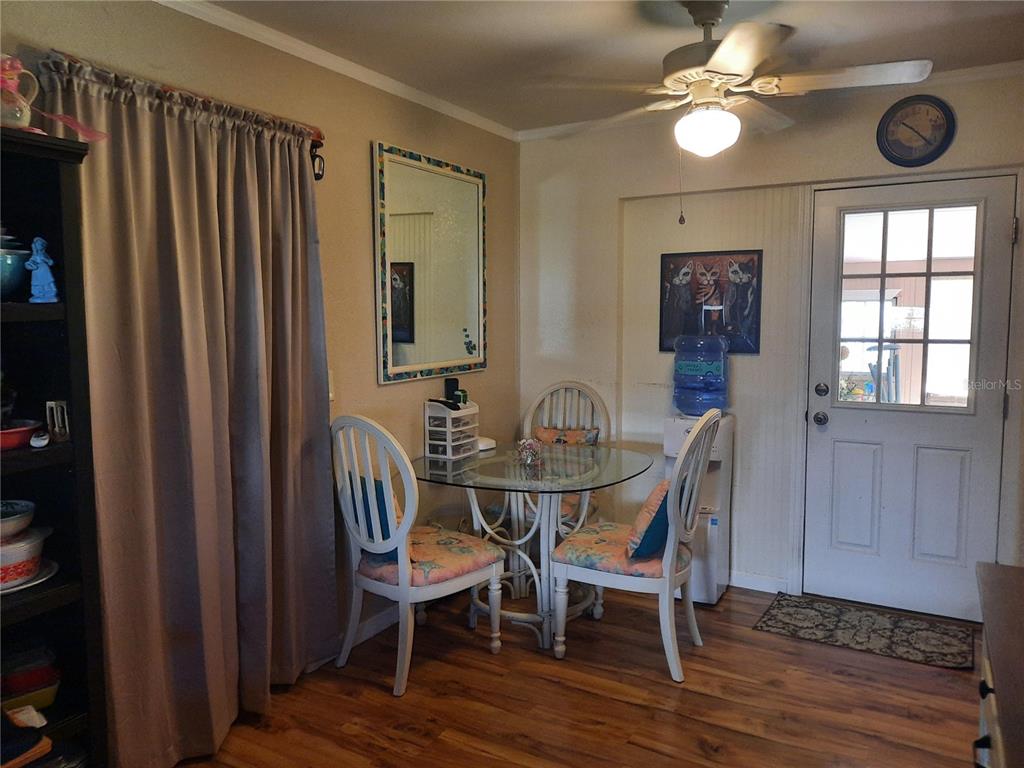 A dining area features a glass-topped table, white chairs, wood flooring, and a ceiling fan — 6554 MALALUKA ROAD, NORTH PORT, FL