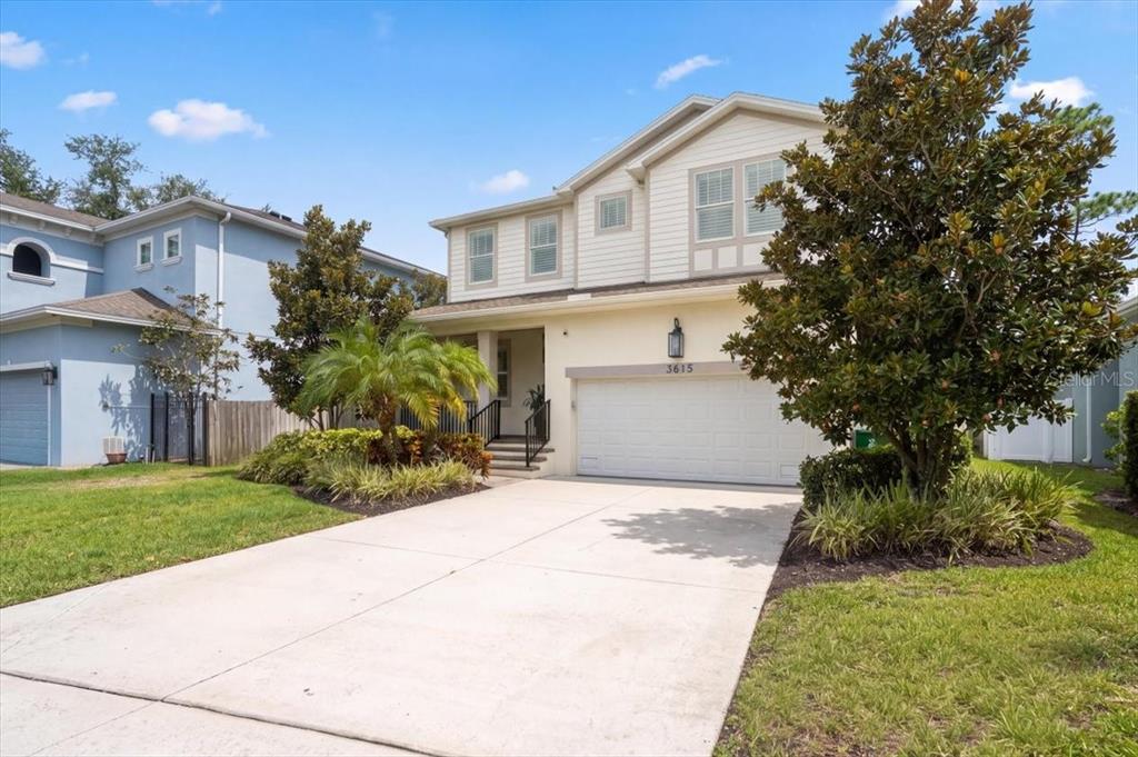 A two-story house with a beige exterior, a two-car garage, and a concrete driveway — 3615 W RENELLIE CIRCLE, TAMPA, FL