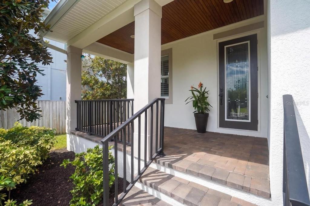 A covered front porch with stone steps, black railings, and a glass-paneled front door — 3615 W RENELLIE CIRCLE, TAMPA, FL
