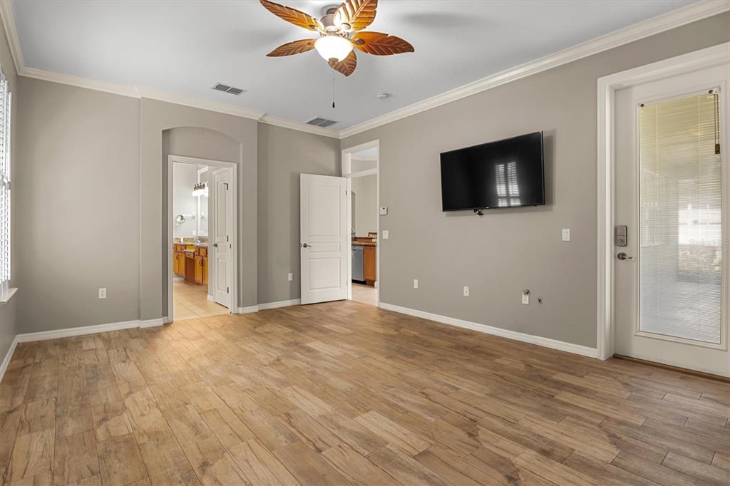 A bedroom with gray walls, wood-look tile flooring, a ceiling fan, and a wall-mounted television — 8281 LAKE JAMES DRIVE, LAKELAND, FL