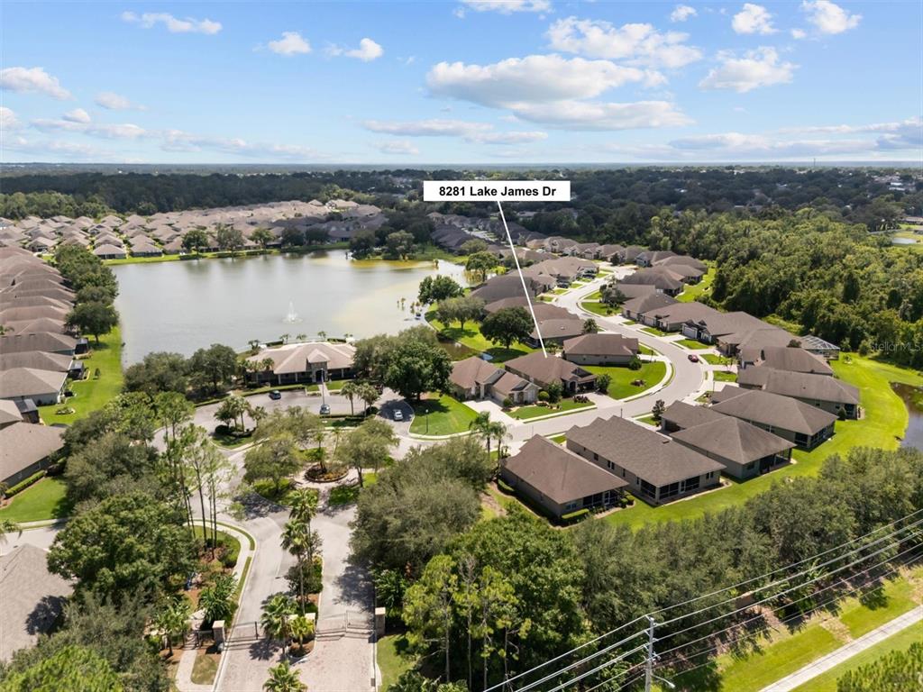 An aerial view shows a residential neighborhood with a lake and a gated entrance — 8281 LAKE JAMES DRIVE, LAKELAND, FL