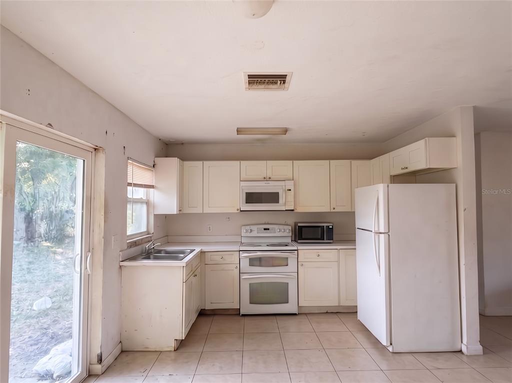A kitchen with white cabinets, white appliances, and light-colored tile flooring — 1636 SE ARAPAHO AVENUE, STUART, FL