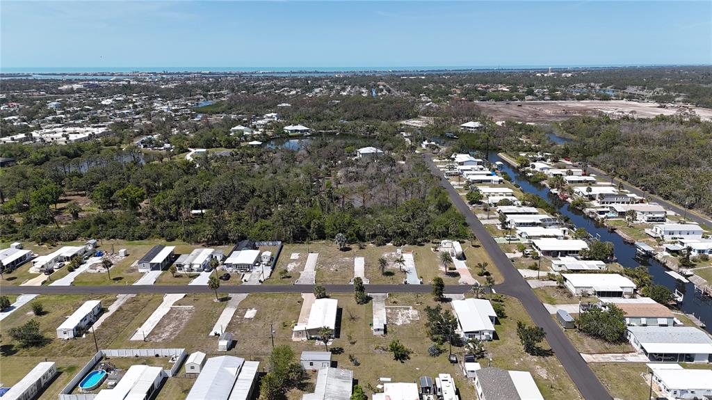 An aerial view shows a residential community with mobile homes, a canal, and surrounding vegetation — 1256 IBIS DRIVE, ENGLEWOOD, FL