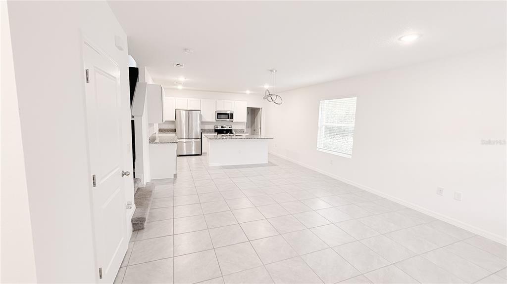 An open-concept kitchen with white cabinets and a center island overlooks a tiled living area — 701 COSTA LANE, DEBARY, FL