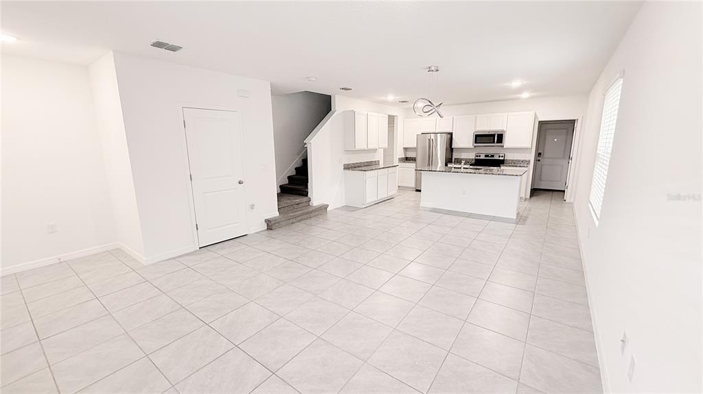 An open-concept kitchen and living area featuring white cabinets, granite countertops, and tile flooring — 701 COSTA LANE, DEBARY, FL