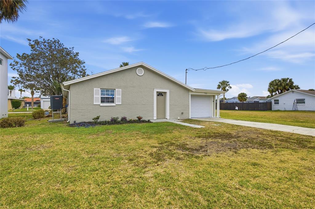 A single-story house with a light-colored exterior, a garage, and a large front lawn — 7410 MAKO DRIVE, HUDSON, FL