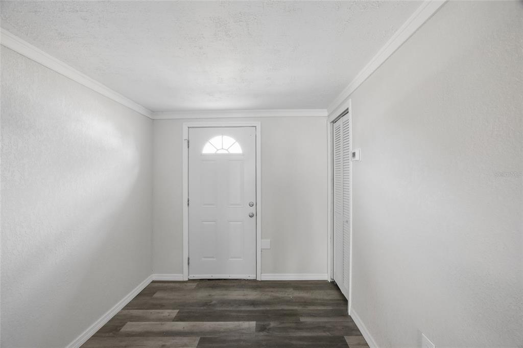 An entryway features light gray walls, dark wood-look flooring, a white front door, and a closet — 7410 MAKO DRIVE, HUDSON, FL