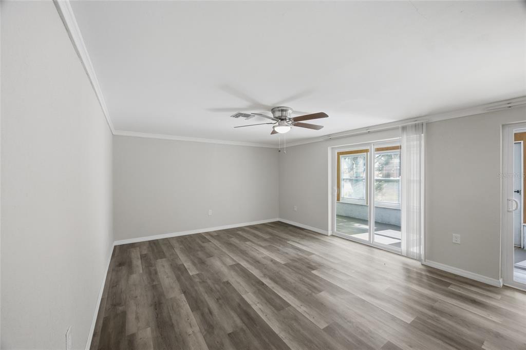 An empty room with light gray walls, wood-look flooring, a ceiling fan, and sliding glass doors — 7410 MAKO DRIVE, HUDSON, FL